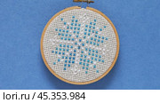 Video of hand embroidered cross stitch snowflake in wooden hoop on blue background. Winter crafts, needlework and Christmas gifts concept. Cross stitches as a hobby. Flat lay, close-up. Стоковое видео, видеограф Виктория Катьянова / Фотобанк Лори