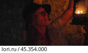 A woman with a kerosene lamp illuminates the stone walls of a dungeon in the dark. Стоковое видео, видеограф Константин Скуридин / Фотобанк Лори