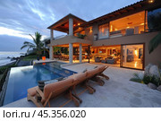 Luxurious oceanfront home with infinity pool enjoying the sunset. Стоковое AI-изображение, AI-художник Иван Рябоконь / Фотобанк Лори