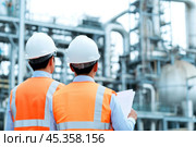Engineers in Safety Gear Conducting Comprehensive Assessments of Industrial Facilities. Civil employees team review project plan at industrial facility factory building. Construction Industry. Outdoor. Стоковое AI-изображение, AI-художник Марина Демидюк / Фотобанк Лори