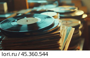 Vinyl records stacked on wooden shelves in a cozy room illuminated by warm afternoon sunlight. Стоковое AI-изображение, AI-художник Сергей Толмачёв / Фотобанк Лори