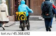 Moscow, Russia, November 08, 2024: food delivery courier on a scooter in the center of Moscow. Редакционное фото, фотограф Igor Skripachev / Фотобанк Лори