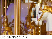 A beautifully designed merrygoround featuring gold and white horses. Стоковое фото, фотограф Аксенова Вера / Фотобанк Лори