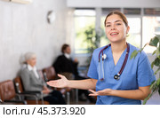 smiling female medical receptionist affably waiting for patients of clinic in waiting room. Стоковое фото, фотограф Яков Филимонов / Фотобанк Лори