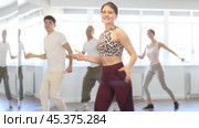 Smiling active young girl enjoying contemporary vigorous dance at group class in light mirrored studio. Стоковое видео, видеограф Яков Филимонов / Фотобанк Лори