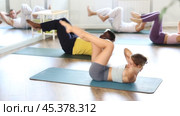 Sporty fit young female pilates instructor leading group classes for men and women of different ethnicities in studio, performing bicycle crunches to strengthen and stabilize abs and obliques. Стоковое видео, видеограф Яков Филимонов / Фотобанк Лори
