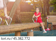 A little girl in the park swings on a balance swing (seesaw or teeter-totter) Стоковое фото, фотограф Nina Kulagina / Фотобанк Лори