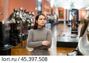 Interested female tourist visiting exhibition of medieval armor in museum. Стоковое фото, фотограф Яков Филимонов / Фотобанк Лори