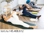 Young asian woman doing Ardha Pawanmuktasana during yoga training. Стоковое фото, фотограф Яков Филимонов / Фотобанк Лори