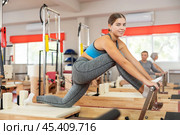 Girl performs exercise on reformer to improve coordination, balance, and posture. Стоковое фото, фотограф Яков Филимонов / Фотобанк Лори