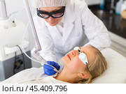 Focused cosmetologist performing laser resurfacing to young woman. Стоковое фото, фотограф Яков Филимонов / Фотобанк Лори