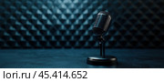 На сцене на темном фактурном фоне стоит старинный микрофон, создающий драматичную и ностальгическую атмосферу. Стоковое AI-изображение, AI-художник ФотоИнтеллект / Фотобанк Лори