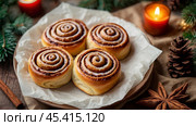 The cinnabons. Close-up of cinnamon buns. Beautiful buns with fresh cinnamon and icing on a wooden table. Fragrant homemade New Year's pastries. Стоковое AI-изображение, AI-художник Photojuli / Фотобанк Лори