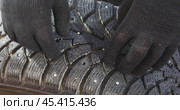 Man inspecting condition of winter tires with studs. Стоковое видео, видеограф Сергей Чайко / Фотобанк Лори