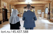 A man and a woman stand with their backs inside the Orthodox Church, Interior wooden Orthodox church of Peter and Fevronia: Belarus - 2020. Стоковое видео, видеограф Дмитрий Нечаев / Фотобанк Лори