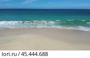 The ocean is calm and the sky is blue. The beach is empty and the waves are small. Стоковое видео, видеограф Дмитрий Брусков / Фотобанк Лори