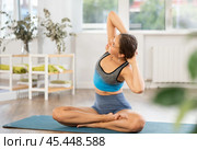 Sportive girl practicing seated side bend pose of yoga in light room. Стоковое фото, фотограф Яков Филимонов / Фотобанк Лори