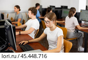 Focused female student in glasses using PC and studying computer science in the classroom. Стоковое фото, фотограф Яков Филимонов / Фотобанк Лори