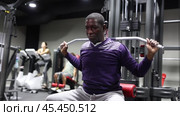 African-american man training on lat pull down machine in gym. Стоковое видео, видеограф Яков Филимонов / Фотобанк Лори