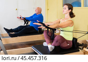 Woman pulling stretch band sitting on pilates training machin. Стоковое фото, фотограф Яков Филимонов / Фотобанк Лори