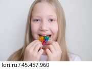 Детская зубная пластина радужного цвета. Ребенок держит в руках ортодонтическую пластинку, чтобы выровнять зубы и расширить челюсть. Стоковое фото, фотограф Терехова Марина / Фотобанк Лори