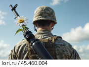 Soldier in a helmet stands with his back to us. A flower is attached to his machine gun. Стоковое AI-изображение, AI-художник Дмитрий Киселёв / Фотобанк Лори
