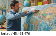 Geography teacher pointing at world map in classroom. Стоковое AI-видео, аниматор Юрий Поздников / Фотобанк Лори