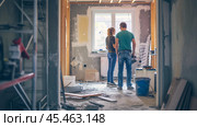 A couple makes a break during renovations. Young attractive couple makes repairs in apartment. Family apartment renovation concept. Стоковое AI-изображение, AI-художник Sergey Grishin / Фотобанк Лори