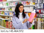 Adult Latina choosing haircare cosmetics in specialized boutique. Стоковое фото, фотограф Яков Филимонов / Фотобанк Лори
