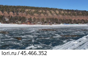 Video of Siberian river Irkut in November during freeze-up. Ice floes float on blue water. On shore is Shamanka village near famous Shamansky cliff, called 33 heroes bogatyrs - natural landmark. Стоковое видео, видеограф Виктория Катьянова / Фотобанк Лори