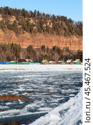 View of Siberian village of Shamanka near beautiful Shamansky cliff on bank of Irkut River in November during freeze-up of river. Сliff is natural landmark of Irkutsk region and place for tourists to travel. Стоковое фото, фотограф Виктория Катьянова / Фотобанк Лори