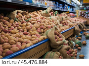Картофель на полке в супермаркете для выбора покупателем и неаккуратно рассыпанный на полу магазина. Potatoes on a shelf in a supermarket for the customer to choose from and carelessly scattered on the floor of the store. Created by Ai. Стоковое AI-изображение, AI-художник Сергей Комаров / Фотобанк Лори
