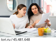 Two women with financial documents near laptop sitting at table at home. Стоковое фото, фотограф Яков Филимонов / Фотобанк Лори