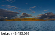A calm blue lake. Ripples on the surface of the water. There are green bushes and yellowed grass on the hilly shore. The clouds in the sky are highlighted. The evening golden hour. Madagascar.Mantasoa. Стоковое фото, фотограф Вера Ивановна Кубарева / Фотобанк Лори