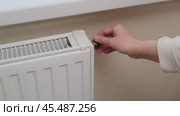 Hand adjusting radiator valve on beige wall background. Close-up of heating system control. Home heating and temperature regulation concept. Стоковое видео, видеограф Андрей Журавлев / Фотобанк Лори