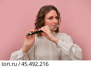 Female musician playing piccolo flute in white blouse against pink background. Studio portrait. Music performance and classical art concept. Стоковое фото, фотограф Андрей Журавлев / Фотобанк Лори