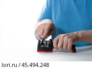 A knife sharpener. A man sharpens a knife on a special universal knife sharpener. Стоковое фото, фотограф Александр Поташев / Фотобанк Лори
