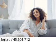 Sweet idleness. Lazy young hispanic lady sit in relaxed pose on big comfy sofa at living room interior breath air dream imagine. Successful female new flat apartment buyer rest at home feel pleasure. Стоковое AI-изображение, AI-художник Sergey Grishin / Фотобанк Лори