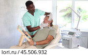 Male cosmetic physician confidently presents patient with visual revelation of remarkable outcomes achieved, leaving patient amazed at positive. Стоковое видео, видеограф Яков Филимонов / Фотобанк Лори