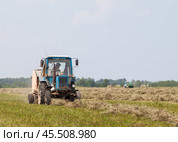"Agricultural machinery in dusty field", "Tractor working on farmland", "Spring cultivation process", "Rural farming scene", Трактор с пресс-подборщиком (2016 год). Редакционное фото, фотограф Сергей Расторгуев / Фотобанк Лори