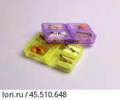 Two pillboxes filled with vitamins, with a reception schedule on a light lilac background. Стоковое фото, фотограф Veronika Belosokhova / Фотобанк Лори