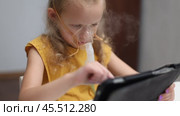A sick girl plays with a tablet and breathes with an inhaler. Стоковое видео, видеограф Кутина Татьяна / Фотобанк Лори