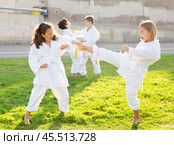 Tweens mastering karate techniques in pairs on green lawn. Стоковое фото, фотограф Яков Филимонов / Фотобанк Лори