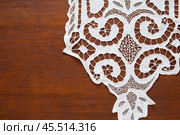 Fragment of white handmade tablecloth with lace patterns embroidered in richelieu style or cutwork embroidery on wooden table. Vintage handicraft for home decoration. Copy space, flat lay, close-up. Стоковое фото, фотограф Виктория Катьянова / Фотобанк Лори