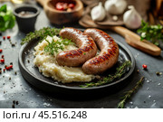 Grilled Sausages, creamy mashed potatoes and fresh parsley. Savory fried sausages and garnish, lunch or dinner. Bratwurst Barbecue. Meat product. Catering. Traditional British dishes, bangers and mash. Стоковое AI-изображение, AI-художник Марина Демидюк / Фотобанк Лори