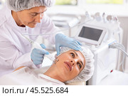 Young female client receiving hardware ultrasonic to revitalize and tighten facial skin at clinic. Стоковое фото, фотограф Яков Филимонов / Фотобанк Лори