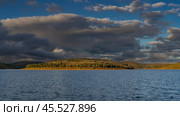 Green trees and yellowed grass grow on the hilly shores of the lake. Ripples on the blue water. The clouds in the sky are highlighted. The evening golden hour. Madagascar. Mantasoa Lake. Стоковое фото, фотограф Вера Ивановна Кубарева / Фотобанк Лори
