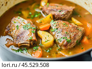 Delicious braised country style pork ribs simmering in a pot with vegetables and broth. Стоковое AI-изображение, AI-художник Юрий Поздников / Фотобанк Лори