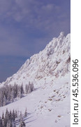 Vertical video: A slow panoramic shot of a rocky mountain peak taken in winter after a recent snowfall. Вертикальное видео: Медленная панорама вдоль скалистой горной вершины, снятая зимой после снегопада. Редакционное видео, видеограф Валерий Тесаков / Фотобанк Лори