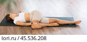 Experienced girl fitness club teacher performs supta ardha matsyendrasana. Стоковое фото, фотограф Яков Филимонов / Фотобанк Лори